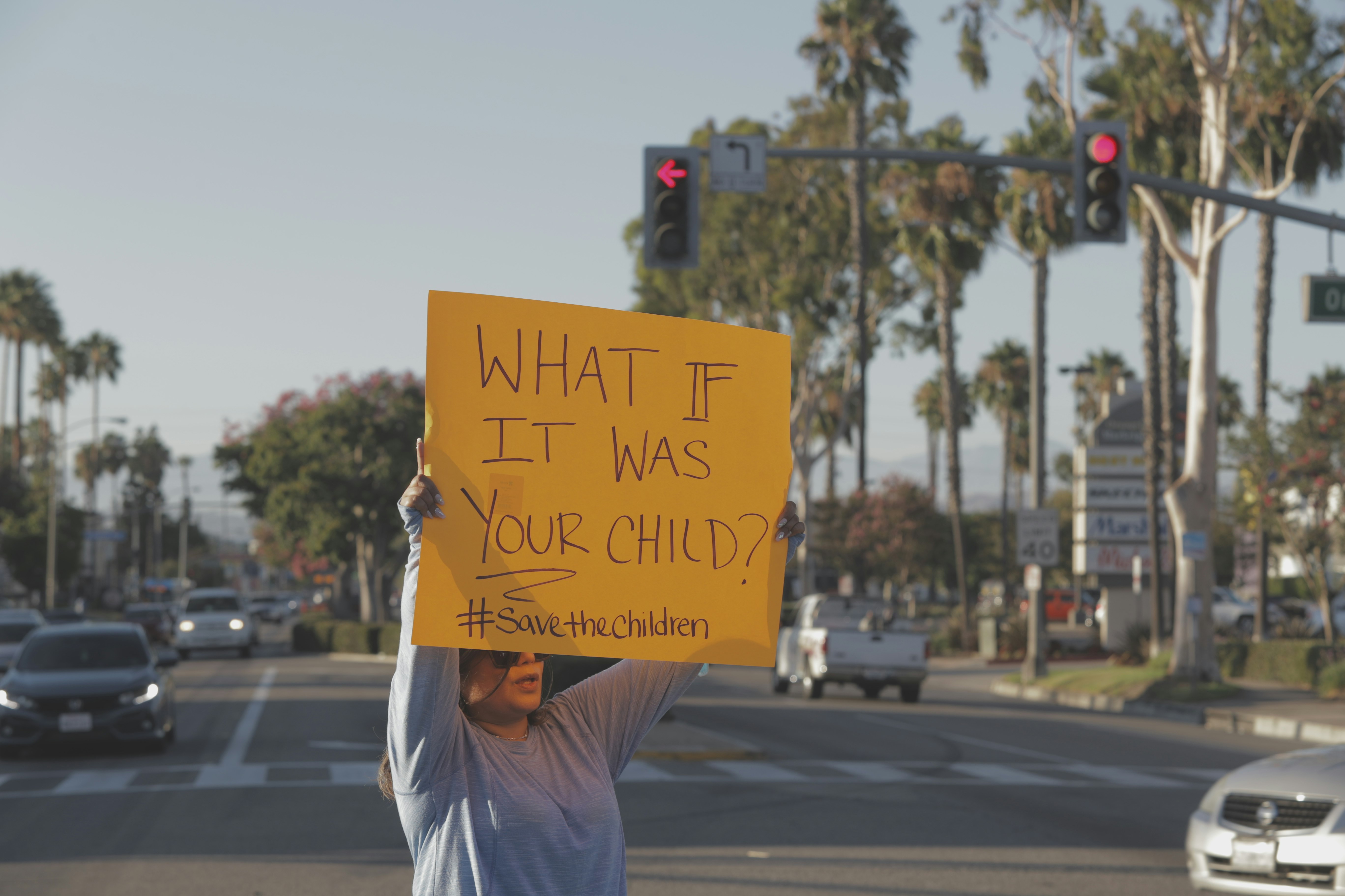 man in white t-shirt holding yellow and black road sign